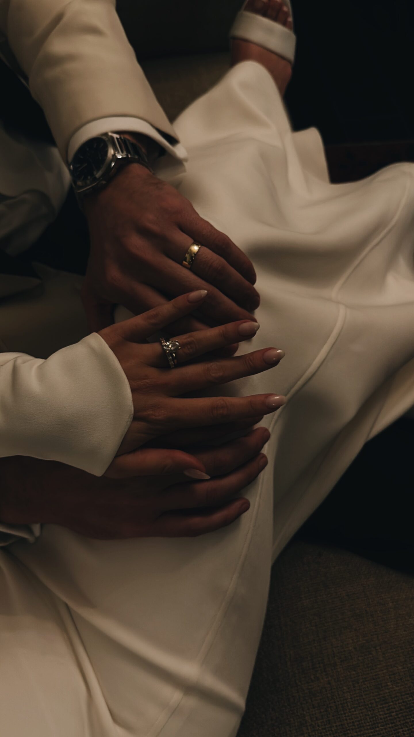 Couple holding hands wearing wedding rings.