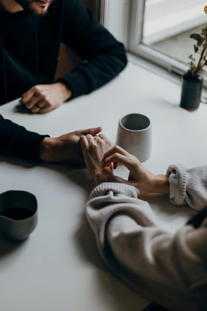Friends holding hands over coffee.