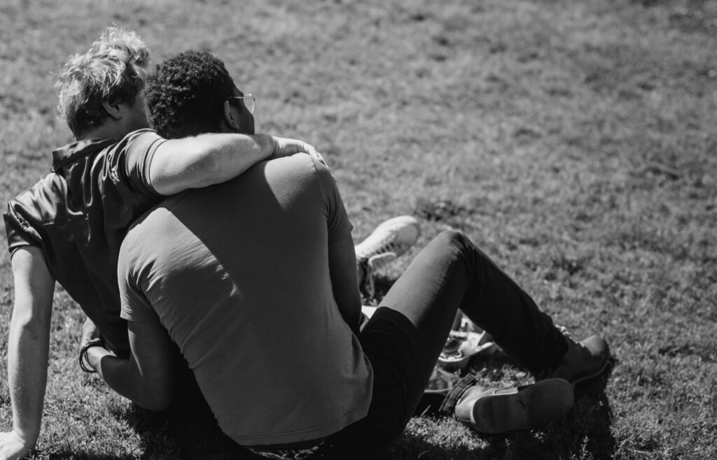 Black and white photo of couple hugging in the grass.