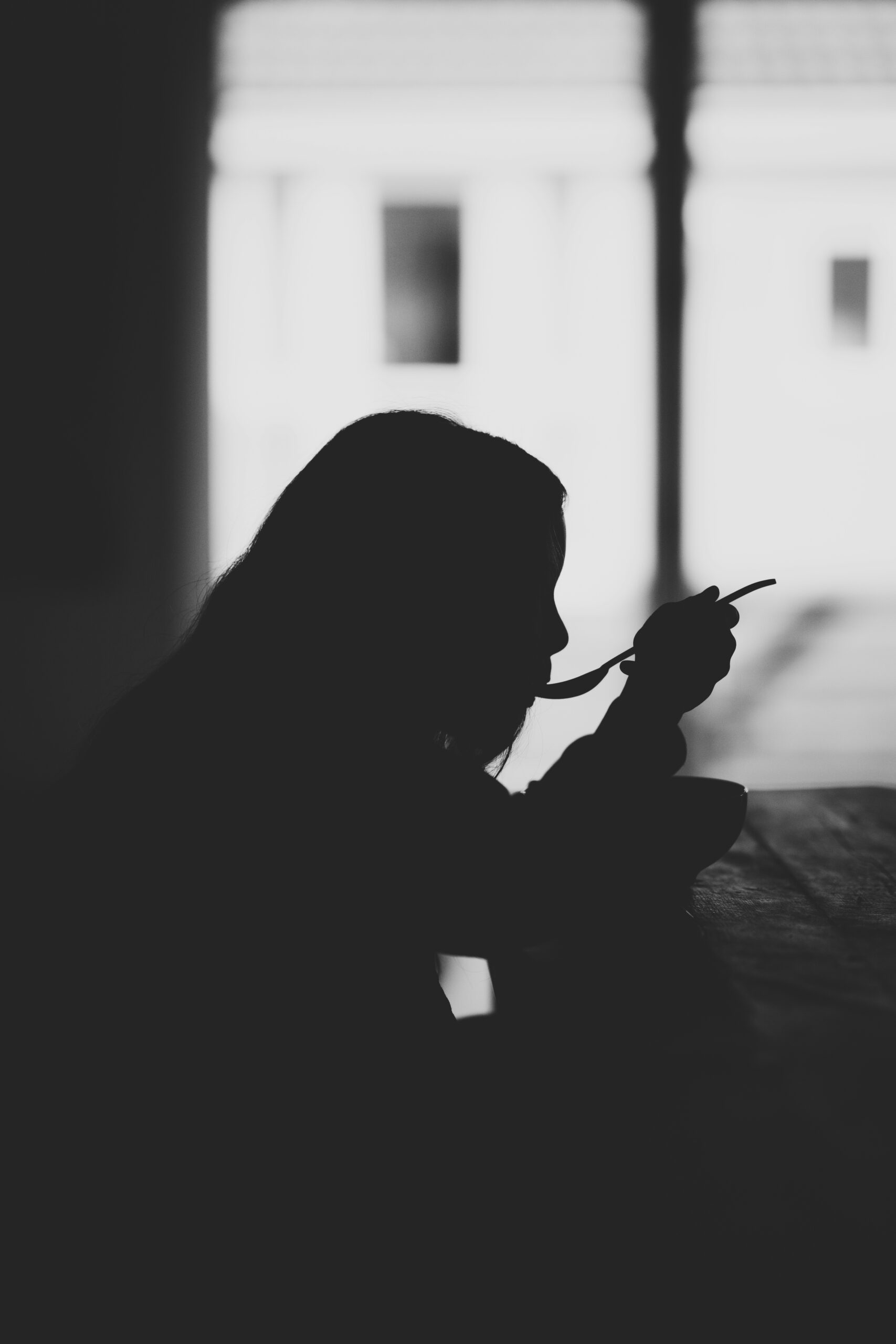 Black and white image of woman eating at table.