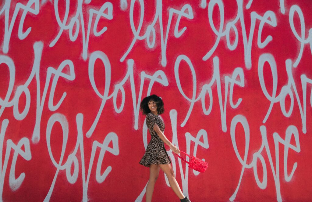 Woman smiling and walking in front of a wall that says 'love'