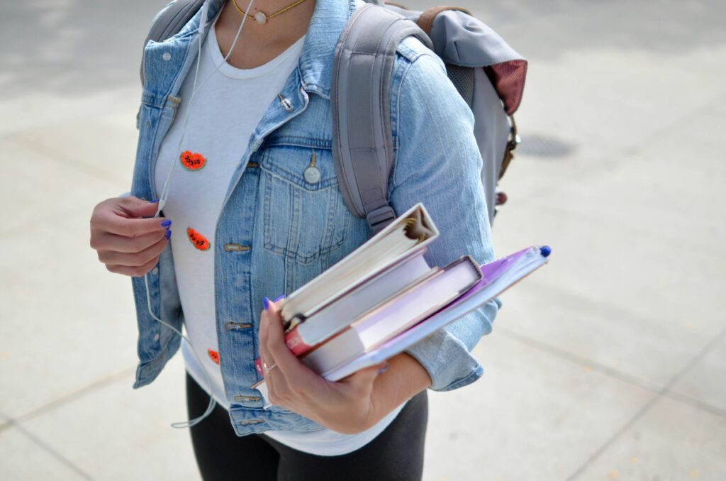 girl listening with her headphones and carrying books to class