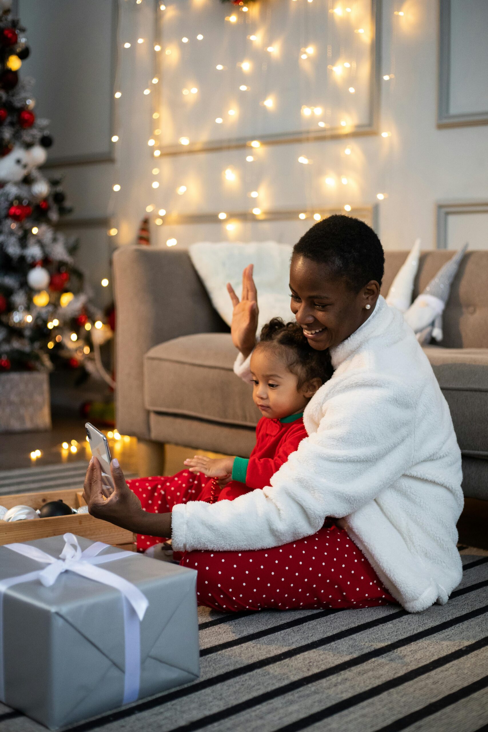 Mom and daughter happy together on the phone in front of Christmas tree.
