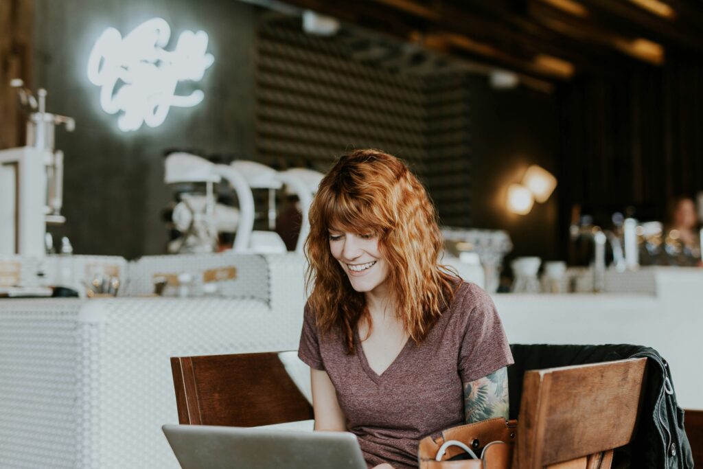 woman smiling looking at her computer in a cafe
