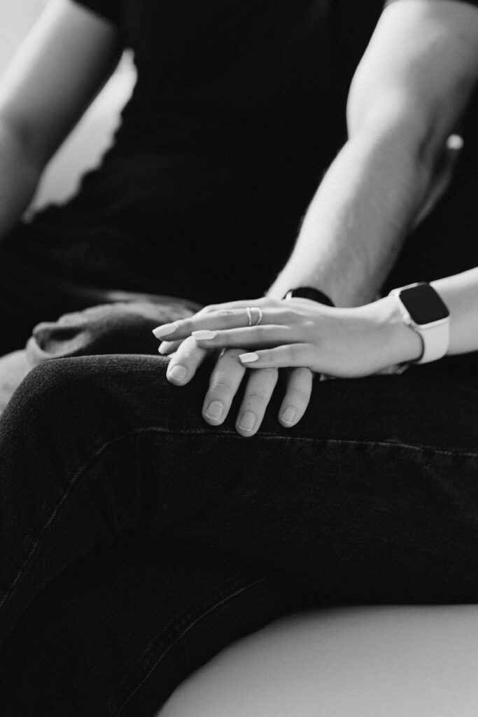 Black and white photo of couple holding hands on a leg,