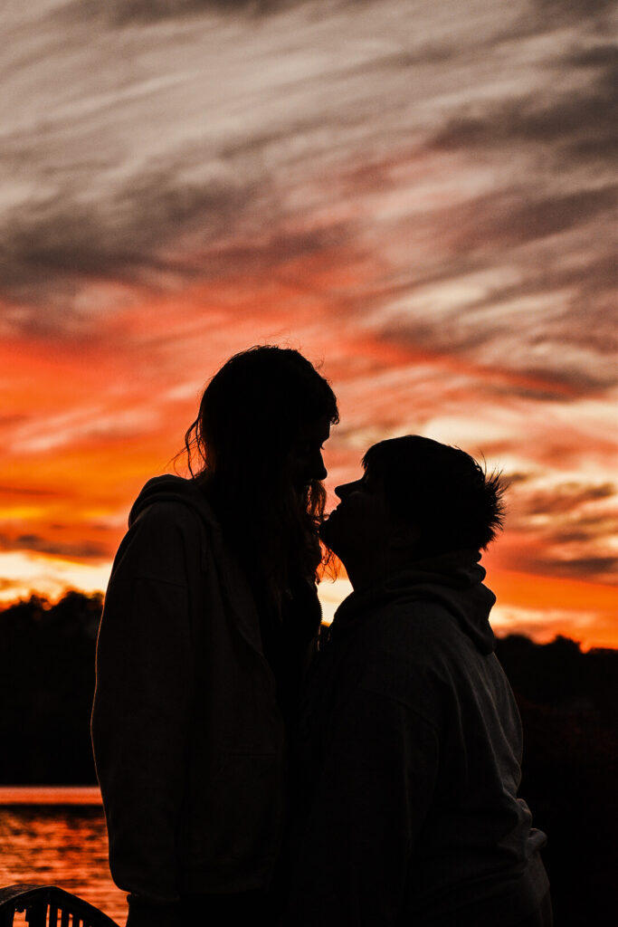 Couple kissing infront of sunset.