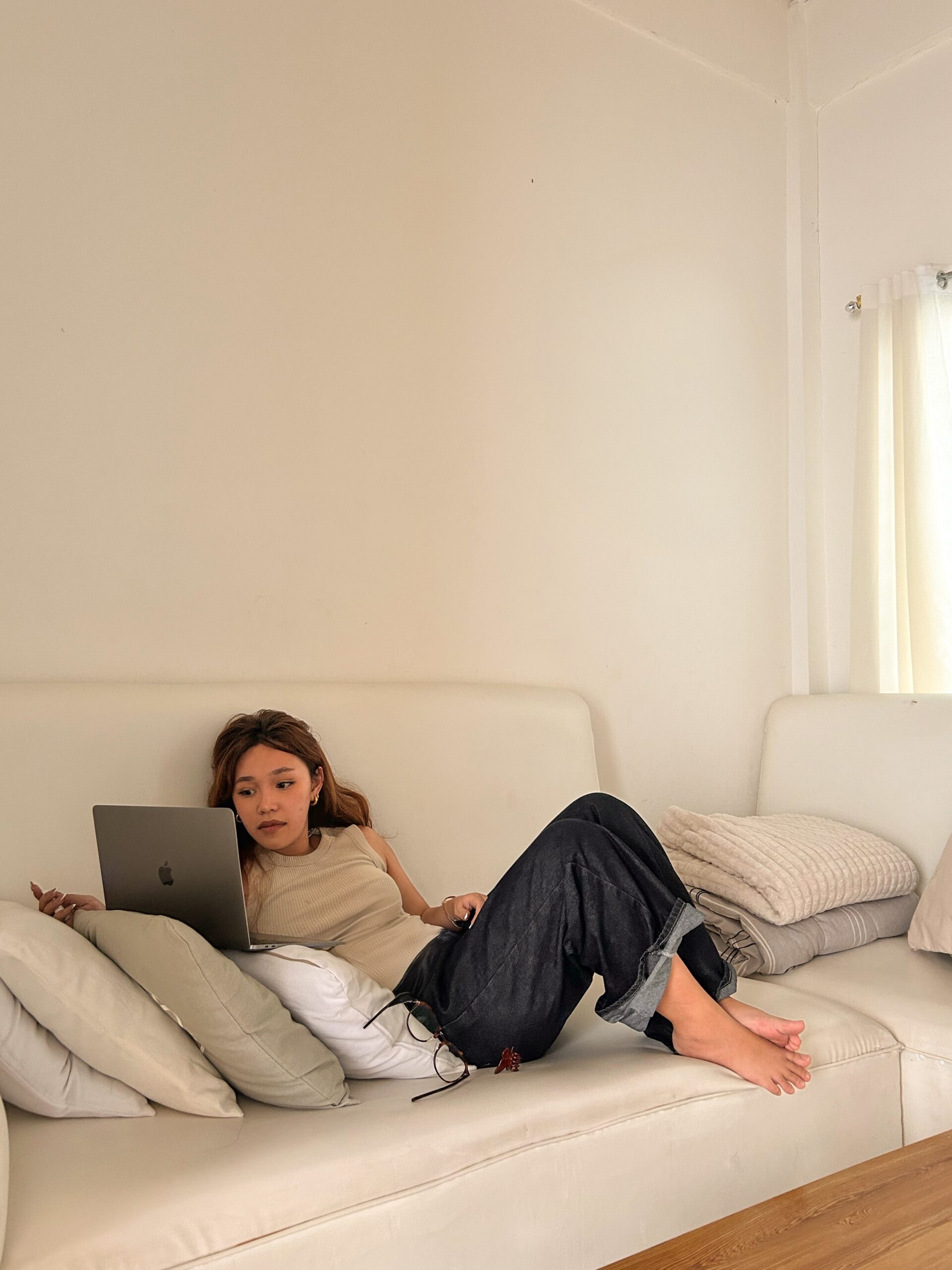 Woman sitting comfortably on a couch at Manhattan Wellness scrolling through a dating app