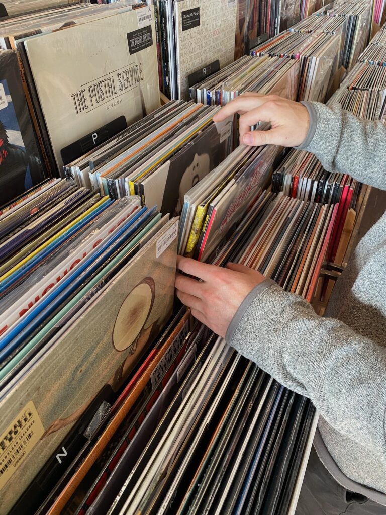 A person picking through a stack of vinyls to listen to in a shop at Brooklyn