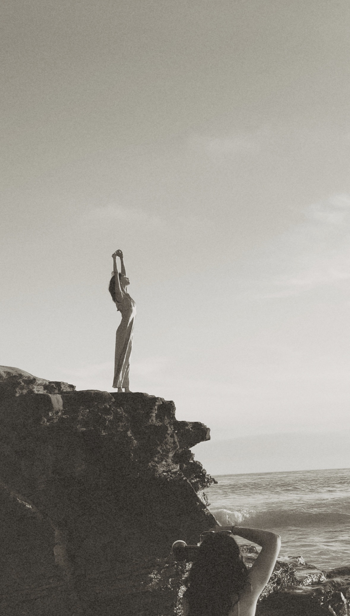 Woman on the end of a cliff stretching and free