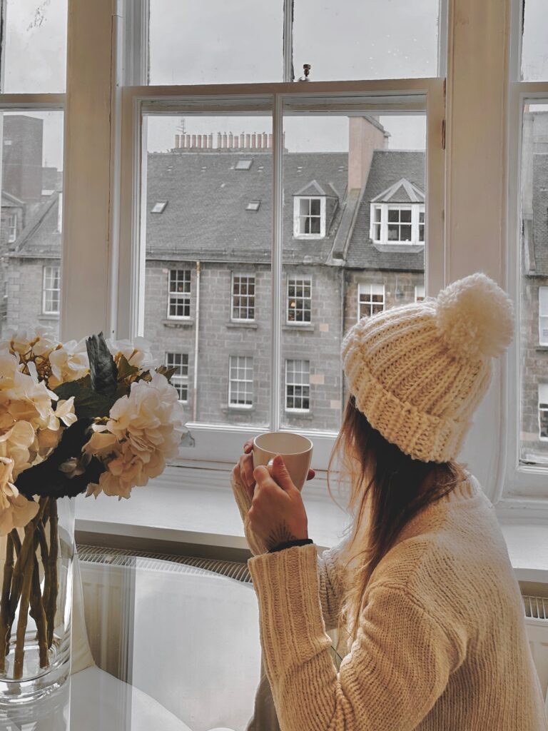 Woman holding a cup while looking at the snow outside in Manhattan 