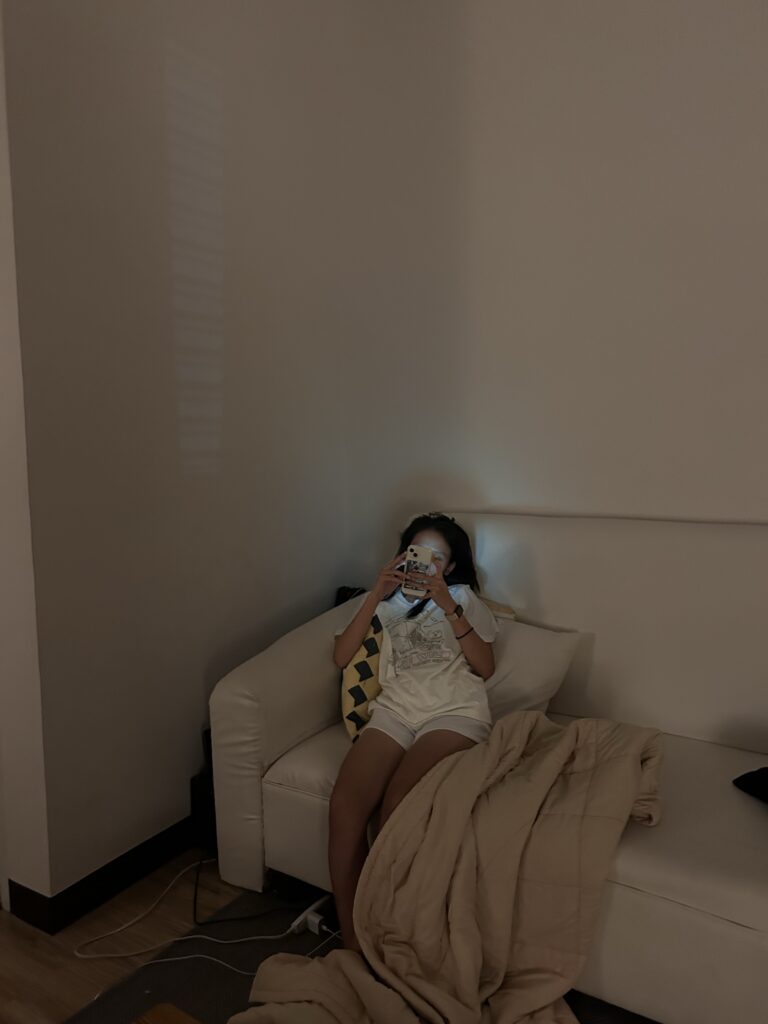 Girl scrolling through old photos of her boyfriend missing him while sitting at her couch in Manhattan