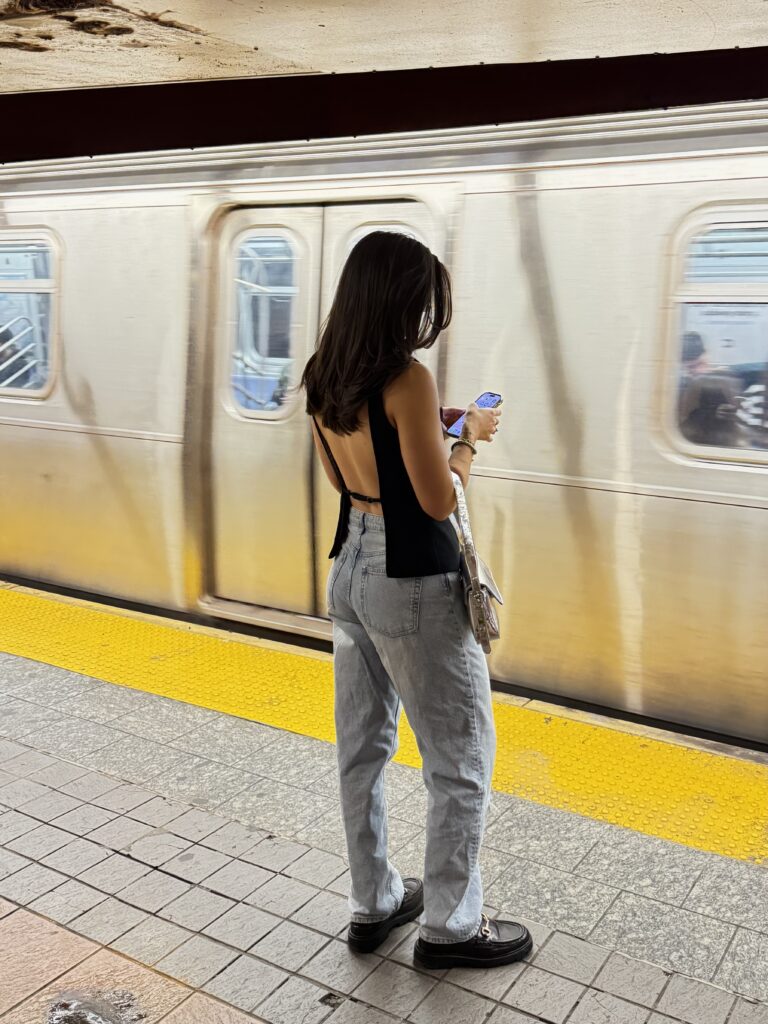Girl standing at the train station scrolling on dating apps in New York