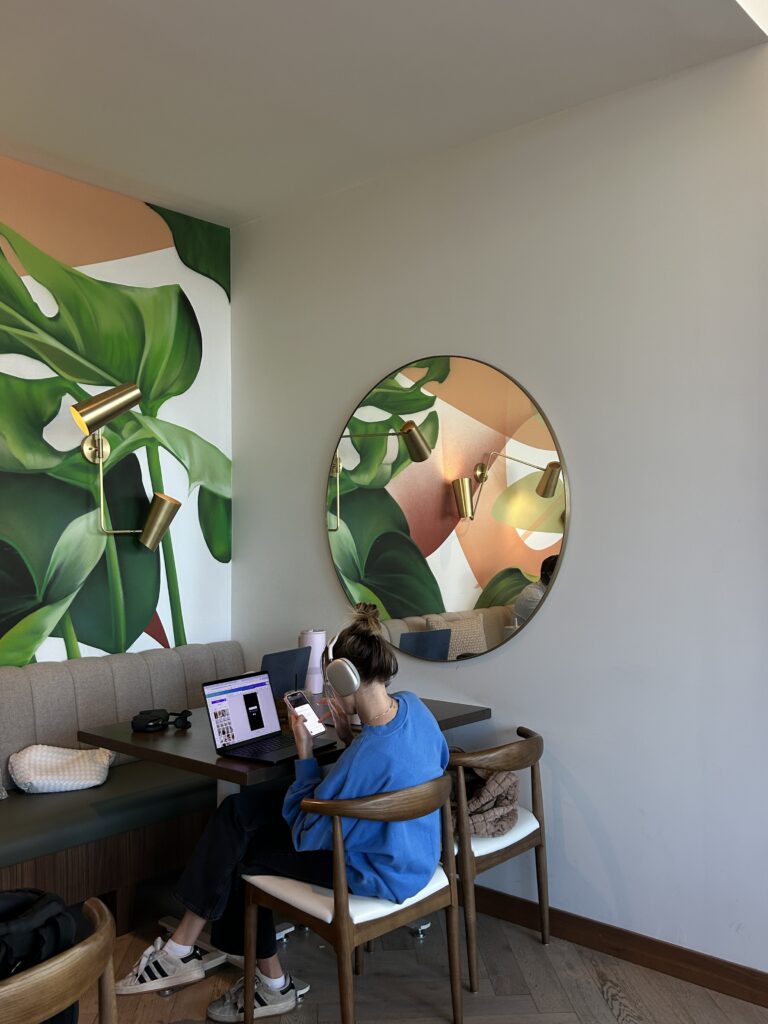 Student sitting in a cafe procrastinating and scrolling through her phone instead of studying at New York