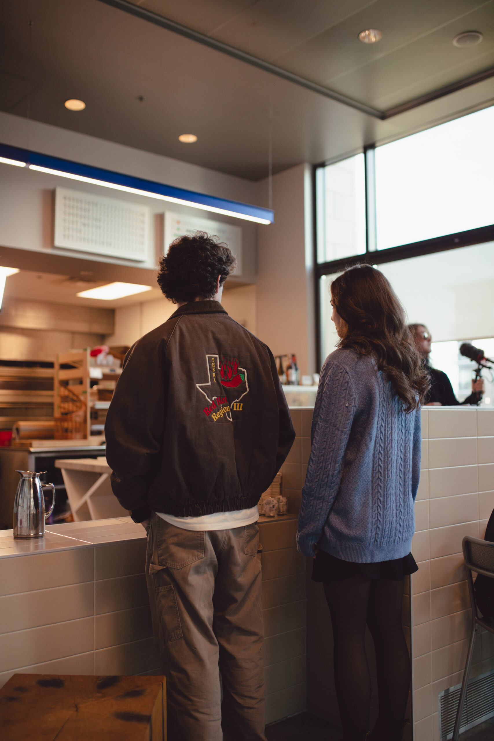 Couple standing apart from each other in a restaurant in Brooklyn