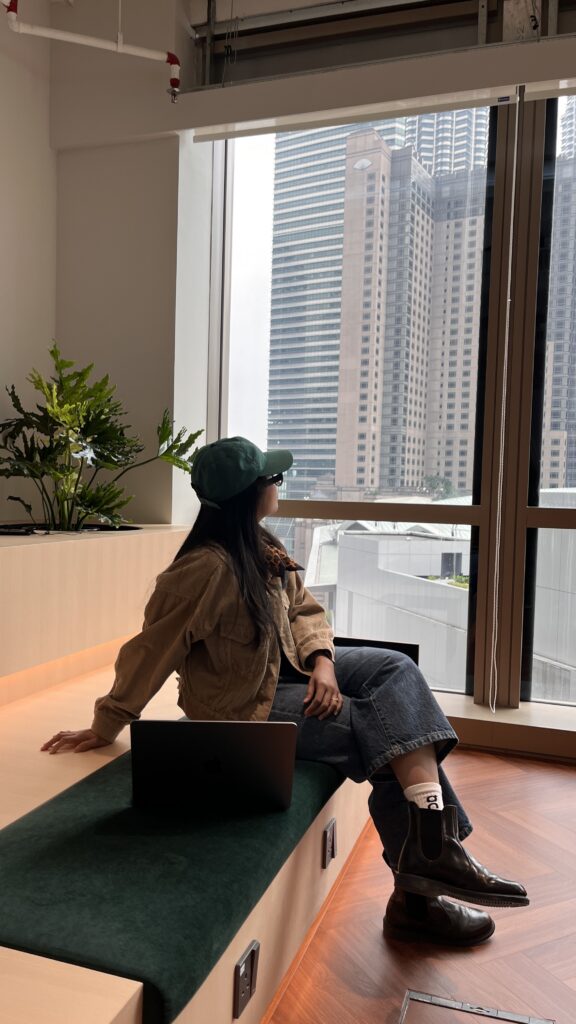 A person sitting alone in a café with a laptop, looking out the window instead of working at Brooklyn