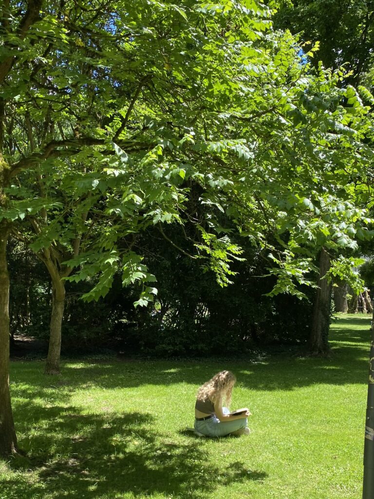 Woman avoiding the noise and pressure of the city by reading a book at the park in Manhattan 