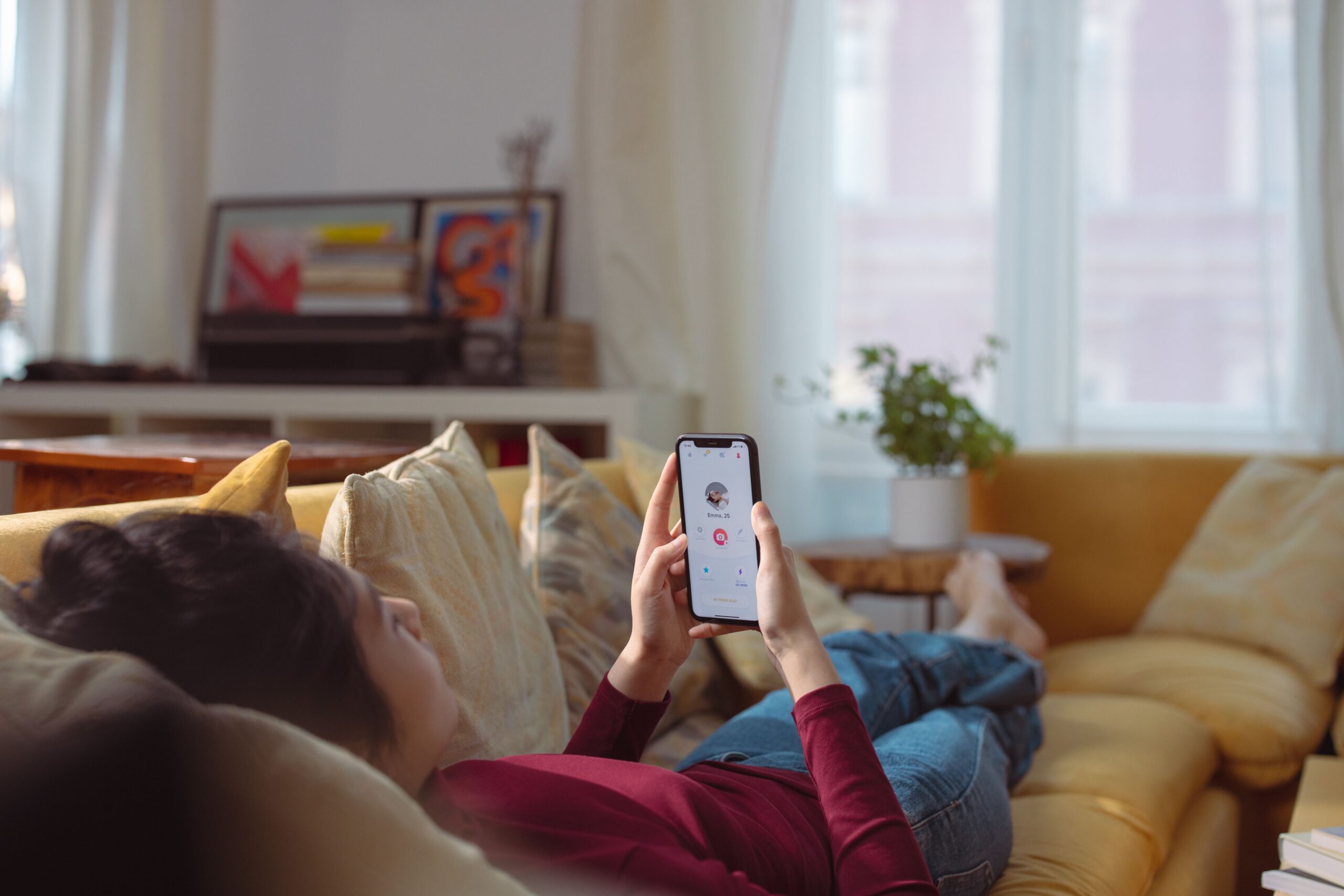 Woman scrolling through dating apps on her couch at Manhattan