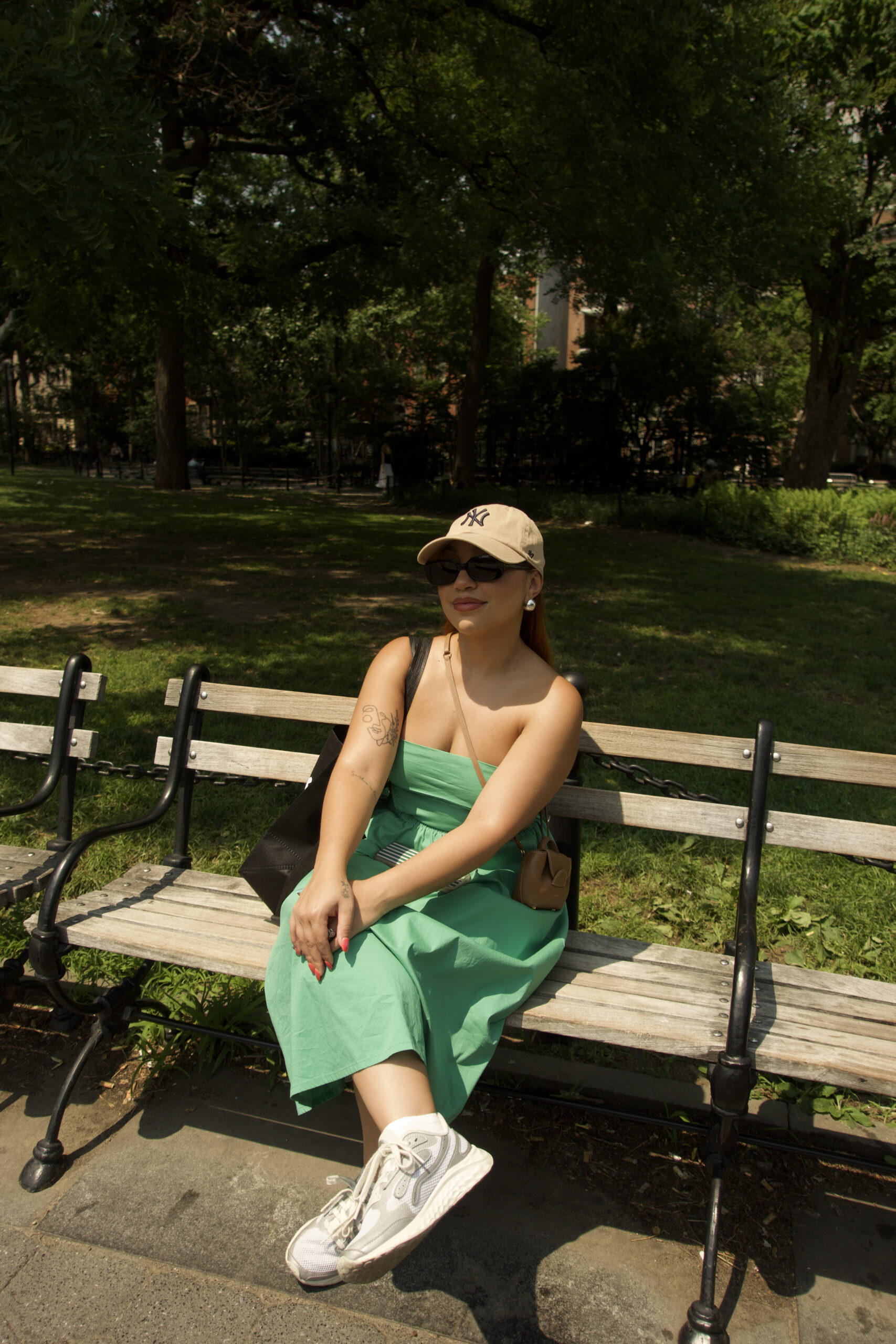 Woman sitting alone on a park bench in summer at New York